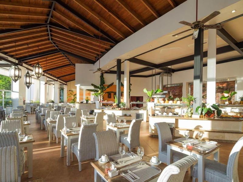 Helles, modernes Restaurant mit Holzdach, vielen Tischen und gemütlichen Polsterstühlen.