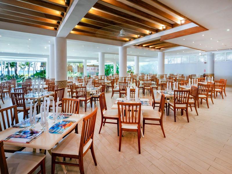 Geräumiges Restaurant mit Holzmöbeln, großen Fenstern und heller, moderner Dekoration.