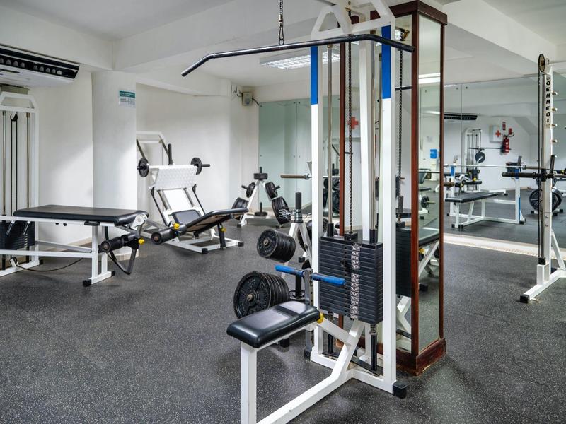 Moderner Fitnessraum mit Geräten, Hanteln und neutralen Farben, gut beleuchtet und sauber.