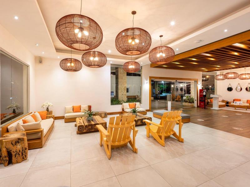 Heller, moderner Wohnbereich mit Holzmöbeln, großen Kronleuchtern und bequemen Sitzgelegenheiten.