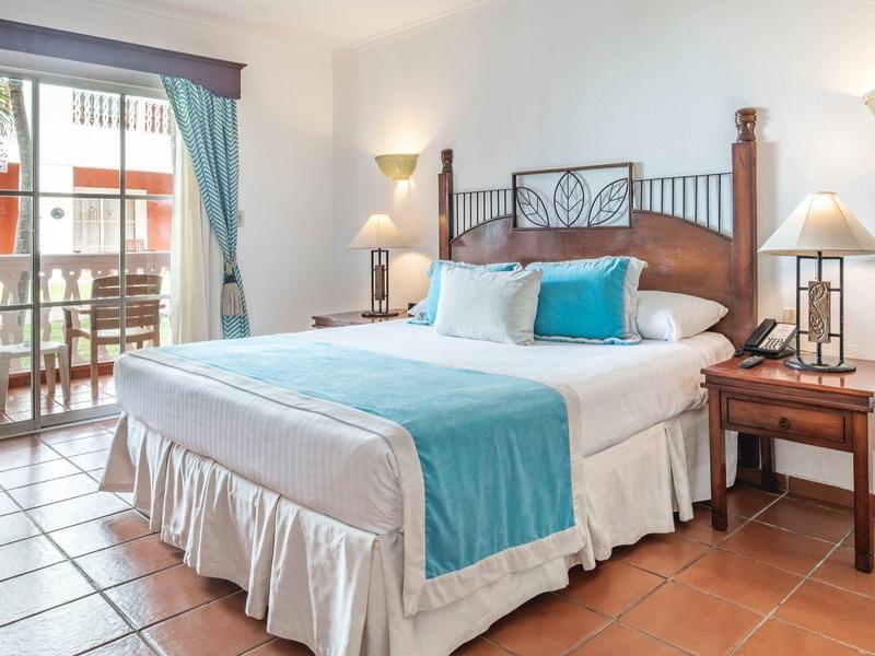 Gemütliches Schlafzimmer mit Doppelbett, blauen Akzenten, Nachtisch und Zugang zum Balkon.