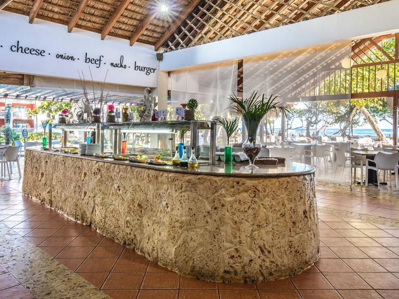 Großer, offener Restaurantbereich mit Natursteinbuffet, Holzdach und viel Tageslicht.