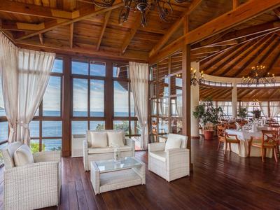 Open lounge area with white rattan furniture and water view.