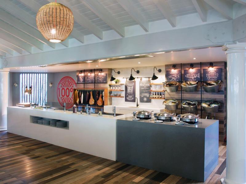 Moderner Buffetbereich mit weißen Theken, Holzboden und Deckenlampen in warmem Licht.