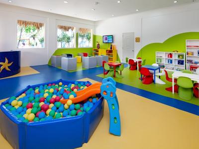 Bunter, moderner Kinderspielbereich mit Bällebad, Rutsche und bunten Teppichen.