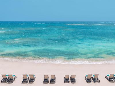 Sandstrand mit Reihen von leeren Liegestühlen und ruhigem türkisfarbenem Meer