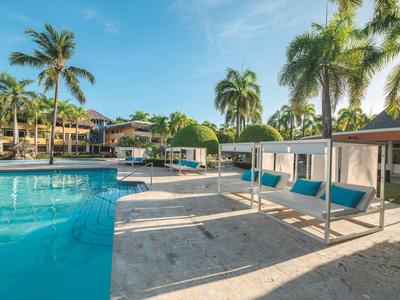 Moderner Poolbereich mit blauen Sonnenliegen und Palmen in einer tropischen Hotelanlage.