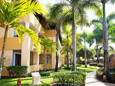 Hotel building with palm trees and well-maintained garden in sunny weather