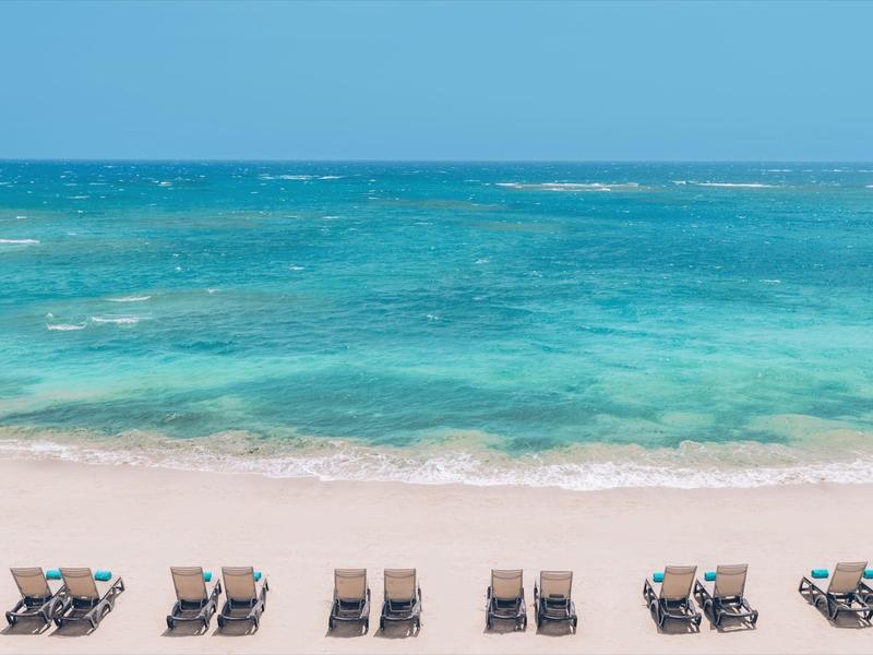 Sandstrand mit Reihen von leeren Liegestühlen und ruhigem türkisfarbenem Meer