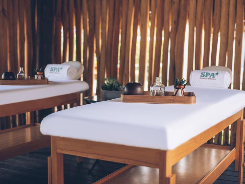 Zwei Massageliegen mit weißen Handtüchern in einem hellen, holzverkleideten Spa-Raum.