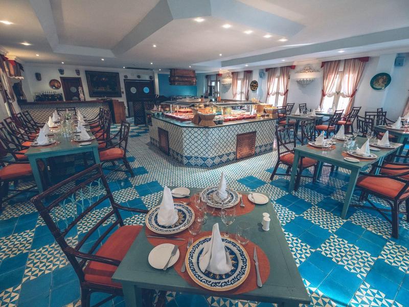 Elegantes Restaurant mit blau-weißem Fliesenboden und gedeckten Tischen mit Servietten.