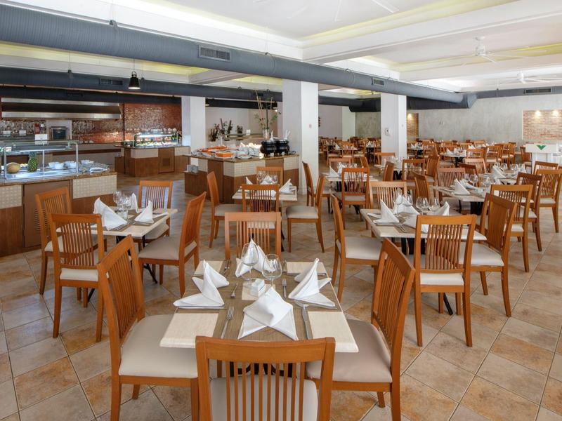 Großer Speisesaal mit vielen Holztischen und Stühlen, gedeckt mit weißen Servietten und Gläsern.