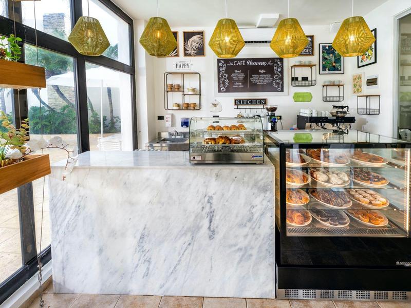 Helle Konditorei mit Marmor-Theke, beleuchteten Kuchenvitrinen und goldenen Hängelampen.