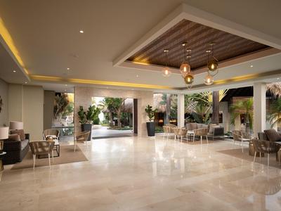 Hell gestaltete Hotellobby mit Marmorboden, moderner Beleuchtung und Sitzbereichen mit Blick auf Garten