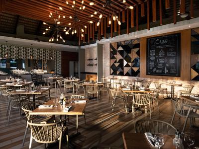 Modernes Restaurant mit Holzdecke, stilvollen Stühlen und Tischen in warmem Licht.