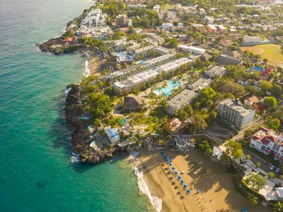 Luftaufnahme einer Küstenstadt mit Stränden, Hotels und klarem blauem Wasser.