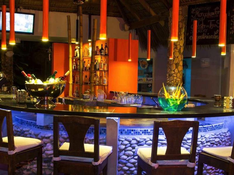 Moderner Barbereich mit hoher Theke, vier Hockern, warmem Licht und dekorativen Elementen.