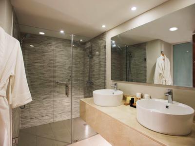 Modernes Badezimmer mit Doppelwaschbecken, großer Spiegel, Duschkabine und beigem Design.