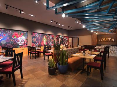 Modernes Restaurant mit holzfarbenem Boden, bunten Wandbildern und gemütlichen Sitzbereichen.