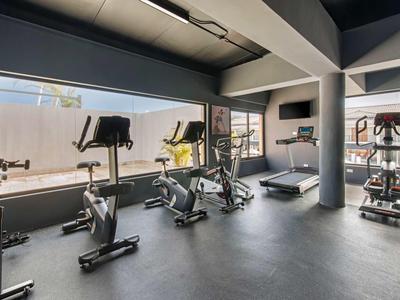 Moderne fitnessruimte met verschillende trainingsapparaten naast grote ramen.