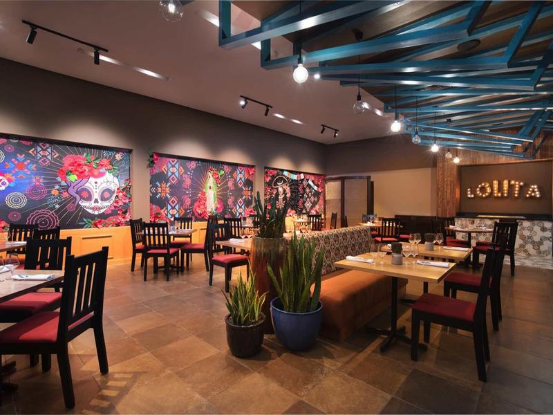 Modernes Restaurant mit holzfarbenem Boden, bunten Wandbildern und gemütlichen Sitzbereichen.