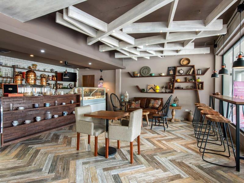 Gemütliches Café mit Holzmöbeln, hoher Decke und großen Fenstern für viel Tageslicht.