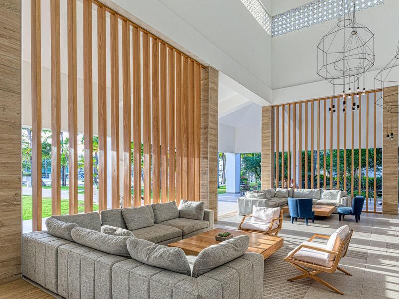 Modernes Hotel-Lobby mit grauem Sofa, Holzvertäfelung und natürlichem Licht.