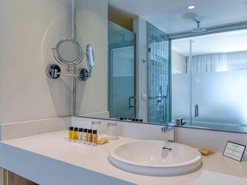 Moderne Badezimmer mit großem Spiegel, rundem Waschbecken, Handtüchern und Pflegeprodukten.