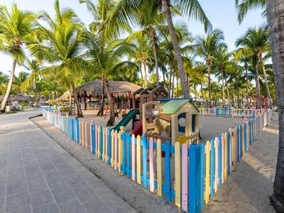 Children's playground with colorful fence and palm trees in a tropical resort.