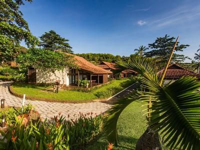 Haus mit rotem Dach und Steinmauern, umgeben von Grün, Blumen und einem gepflasterten Weg.