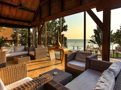 Gemütliche Lounge mit Sofas und Blick auf Strand und Meer bei Sonnenuntergang