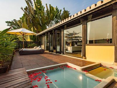 Moderner Außenbereich mit Holzterrasse, kleinem Pool mit Rosenblättern und gemütlicher Sitzgelegenheit.