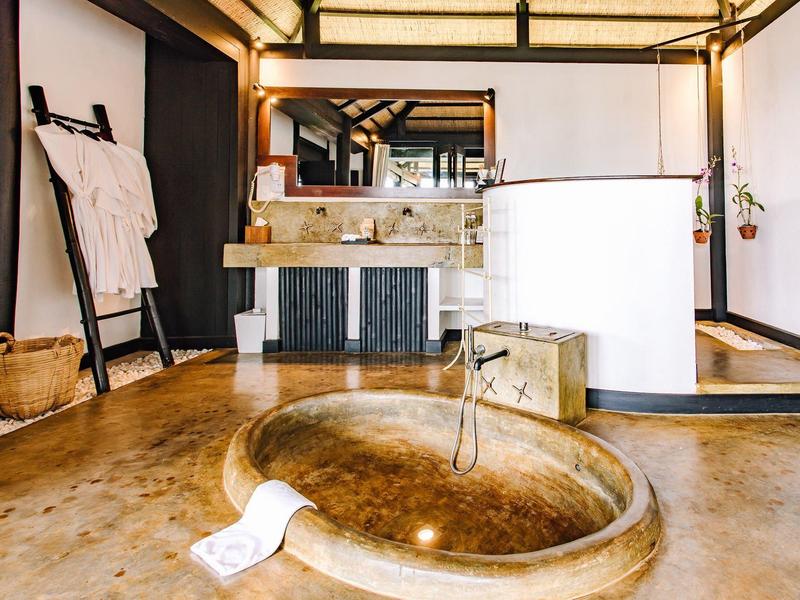 Modernes Badezimmer mit runder Badewanne aus Marmor und Holzleiter für Handtücher.