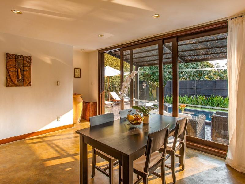 Moderner Essbereich mit dunklem Holztisch, sechs Stühlen und großem Fenster zum Garten mit Pool.