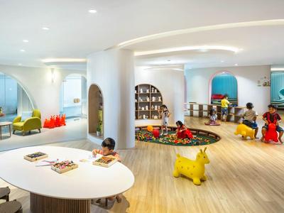Área de juegos infantil luminosa y moderna en hotel, con muebles coloridos y suelo de madera.