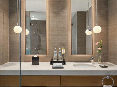 Baño moderno con lavabo doble, dos espejos grandes y una iluminación tranquila.