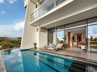 Moderner Balkon mit Pool und Liegestühlen vor großen Glasschiebetüren.