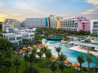 Luxushotel mit mehreren Gebäuden, Pools und tropischen Gärten bei Sonnenuntergang.