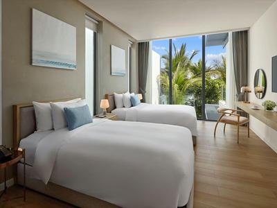 Modernes Hotelzimmer mit zwei großen Betten, Holzboden und Blick auf Palmen durch große Fenster.
