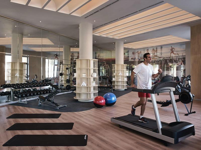 Gimnasio moderno en el hotel con colchonetas, pesas, pelotas de ejercicio y cinta de correr.