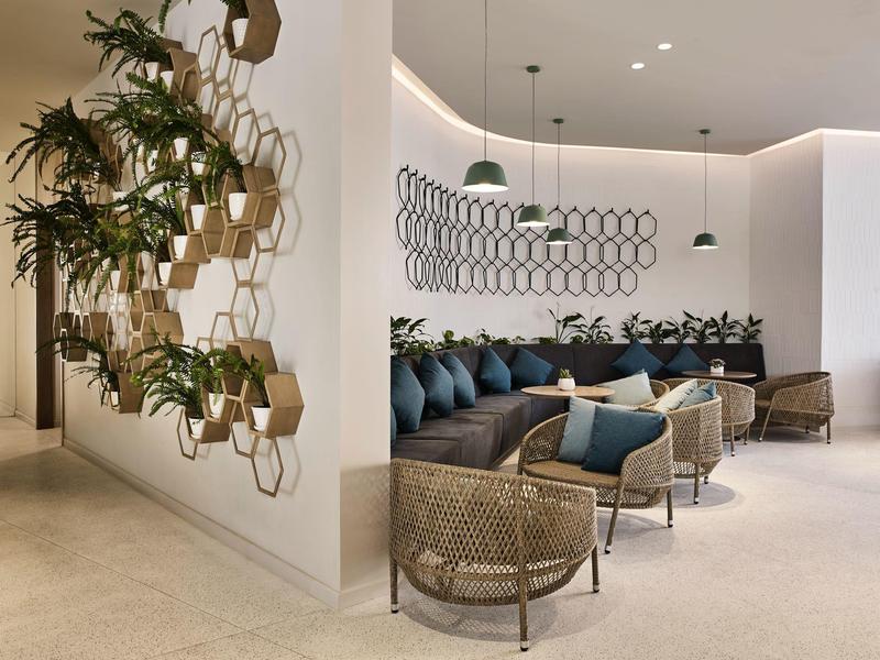 Área de lounge de hotel moderno con decoración de pared de estantes hexagonales y asientos cómodos.