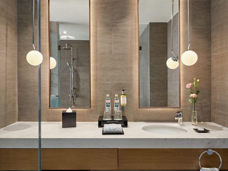 Baño moderno con lavabo doble, dos espejos grandes y una iluminación tranquila.