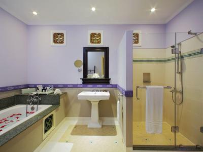 Bathroom with shower, bathtub with rose petals, and sink against purple walls.