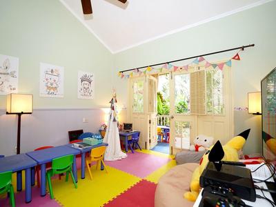 Colorful playroom with small tables, chairs, and balcony access in a bright space.