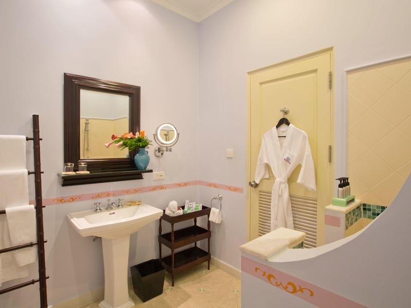 Bright bathroom with sink, mirror, towels, and bathrobe hanging on yellow door hook.