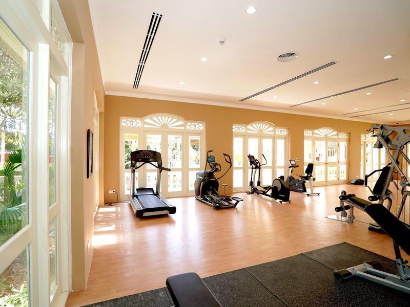 Bright gym with treadmills, weights, and large windows showing outdoor views.