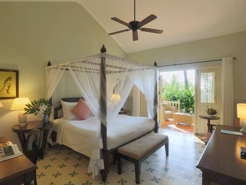Bright bedroom with canopy bed, ceiling fan, and terrace with plants.