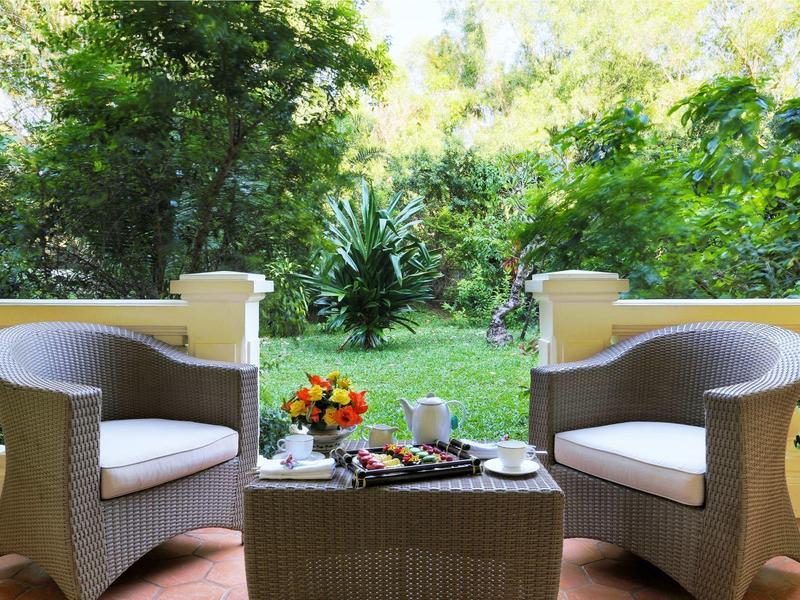 Two wicker chairs with table on terrace overlooking green garden
