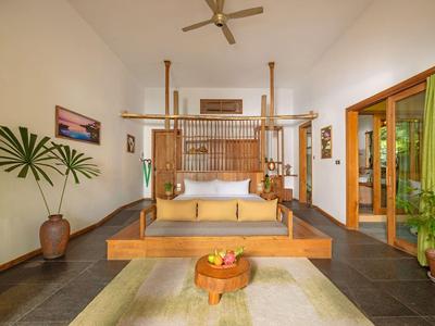 Rustic open-air hotel lobby with wooden beams, chandelier, reception desk, and natural wood furniture.