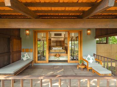 Cozy wooden terrace with lounge chairs and cushions overlooking greenery in a tropical setting.